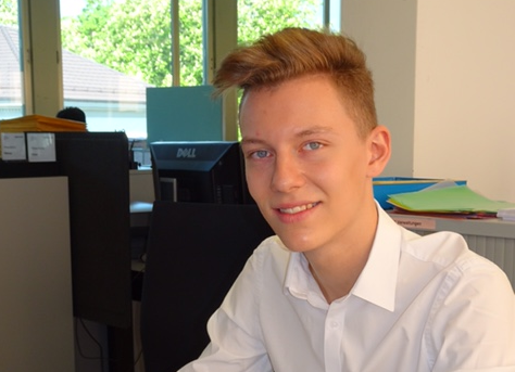 Ein junger Mann im Hemd sitzt an seinem Arbeitsplatz